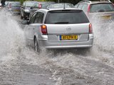 Een auto rijdt door een onder water gelopen straat
